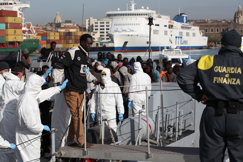 Migranti vystupují z lodi v sicilské Catanii