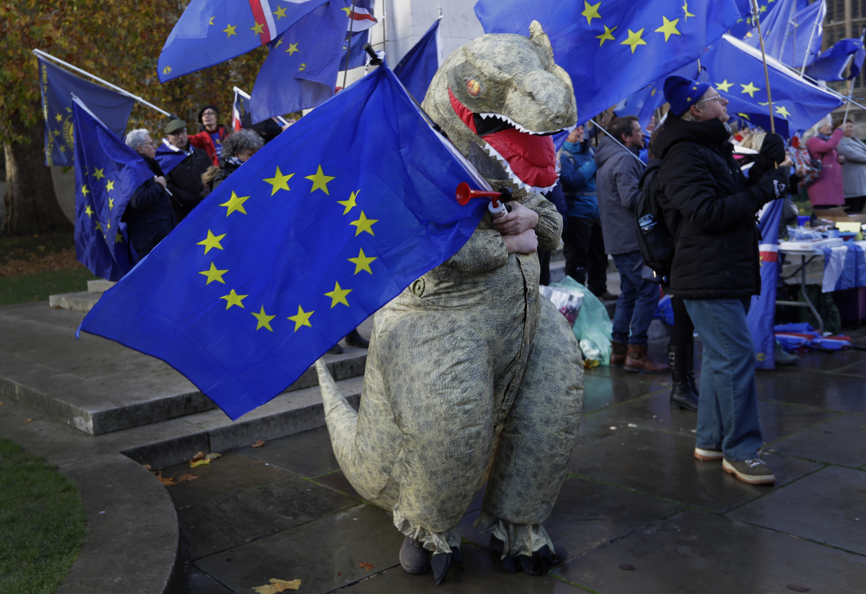 Člověk v masce dinosaura s vlajkou EU