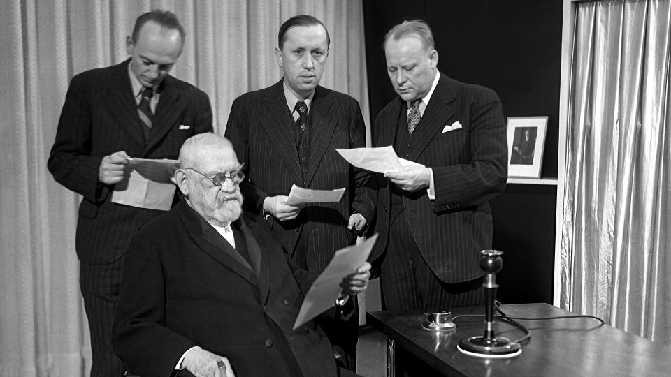 Natáčení mírového poselství „všem lidem dobré vůle“. Zleva stojí Otakar Matoušek, Karel Čapek, Vincenc Lesný, v popředí sedí František Křižík (24. 12. 1937)