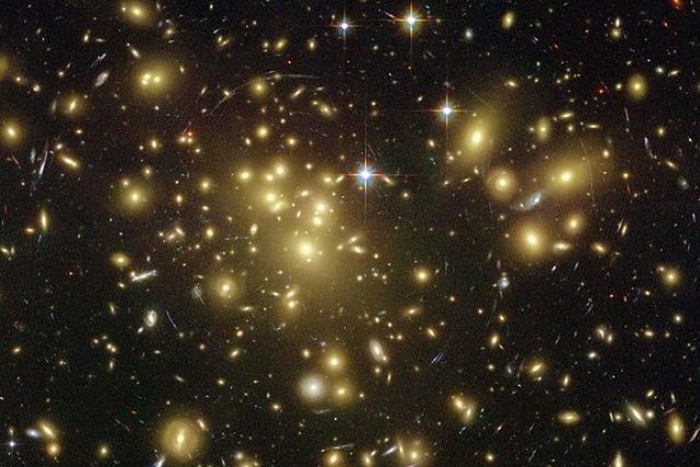 Temná hmota - masivní kupa žlutavých galaxií,  zdánlivě chycená v červené a modré pavučině pokroucených galaxií v pozadí. Snímek z Hubbleova vesmírného teleskopu | foto:  NASA,  N. Benitez  (JHU),  T. Broadhurst  (Hebrew University),  H. Ford  (JHU),  M. Clampin  (STScI),  G. Hartig  (STScI),  G. Illingworth  (UCO/Lick Observatory),  ACS Science Team,  ESA