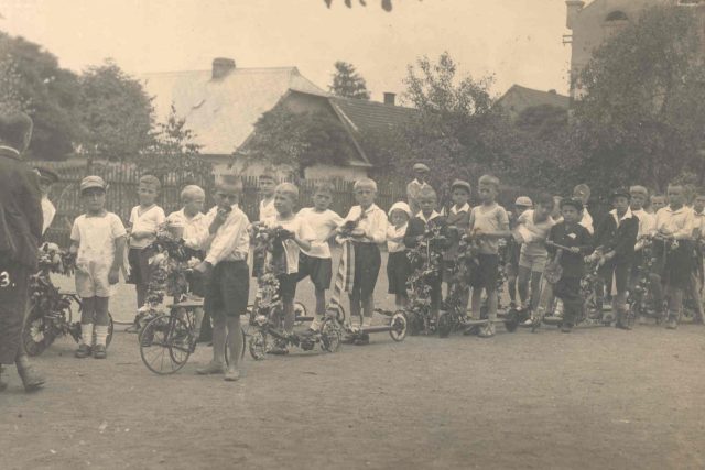 František Wiendl  (v tmavém na koloběžce - druhý z prava),  30. léta,  školní průvod,  Voříškova ulice v Klatovech | foto: Post Bellum