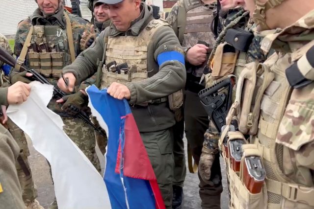 Vjačeslav Zadorenku rozřezává ruskou vlajku ve městě Kozača Lopan v Charkovské oblasti | foto: Facebook Vjačeslava Zadorenka,  Reuters