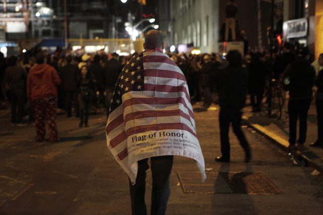 Muž s vlajkou USA míří k davu oslavujícímu smrt Usámy bin Ládina na Ground Zero v New Yorku  (archivní foto,  2. května 2011) | foto: Finbarr O'Reilly,  Reuters