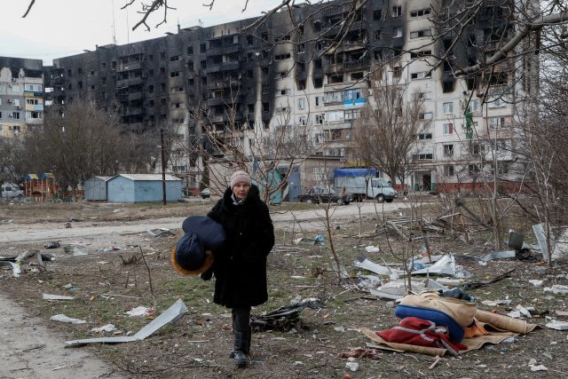 Žena prochází poničenou obytnou zónou v ukrajinském Mariupolu | foto: Alexander Ermochenko,  Reuters