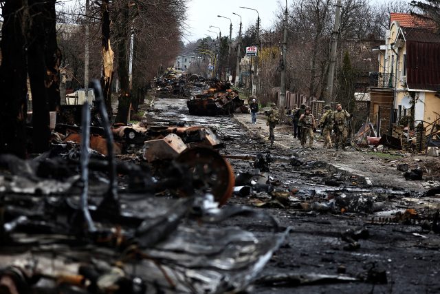 Vojáci prochází kolem zničené ruské techniky ve městě Buča nedaleko Kyjeva | foto: Reuters