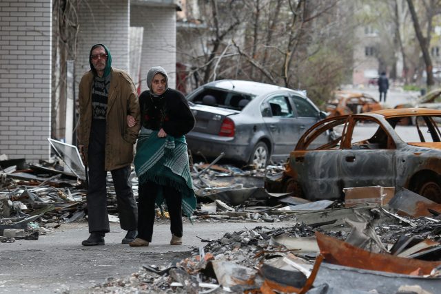 Obyvatelé Mariupolu procházejí kolem zničených aut | foto: Reuters