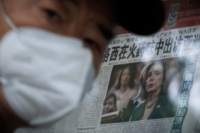 Muž v Pekingu u novinového stánku,  ve kterém noviny informují o cestě americké předsedkyně sněmovny Nancy Pelosiové | foto: Thomas Peter,  Reuters
