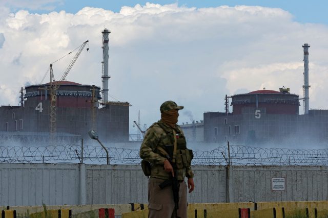Voják s ruskou vlajkou na uniformě poblíž Záporožské jaderné elektrárny | foto: Reuters