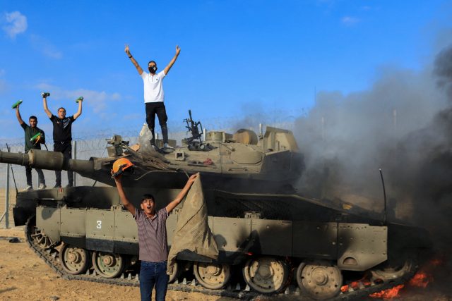 Palestinci oslavují hořící izraelské vojenské vozidlo zasažené palestinskými ozbrojenci,  kteří pronikli do oblastí jižního Izraele | foto: Reuters