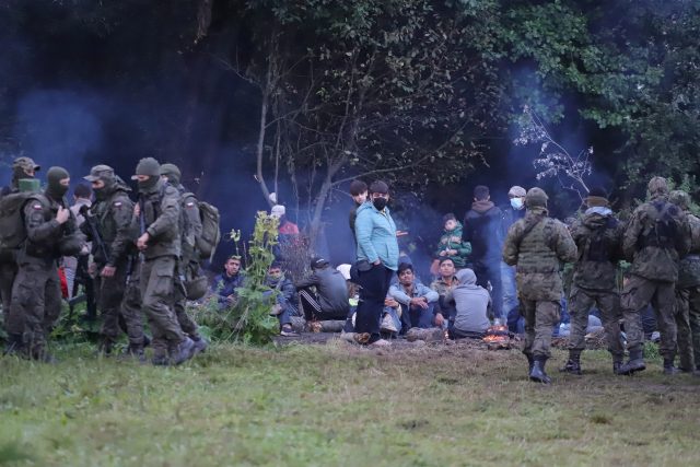 Polští pohraničníci hlídají skupinu migrantů,  kteří se pokusili překročit hranici mezi Běloruskem a Polskem poblíž vesnice Usnarz Gorny v Polsku | foto: Reuters