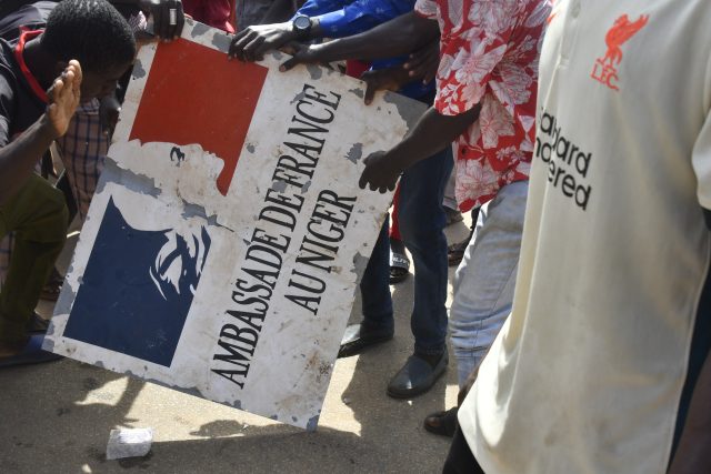 Demonstranti drží nápis stržený z francouzského velvyslanectví v Niamey  (Niger) během demonstrace na podporu nigerské junty | foto: Profimedia