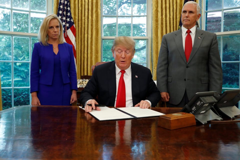 Americký prezident Donald Trump  (uprostřed)  podpisuje migrační dekret. Přihlíží viceprezident Mike Pence  (vpravo). | foto: Leah Milllis,  Reuters